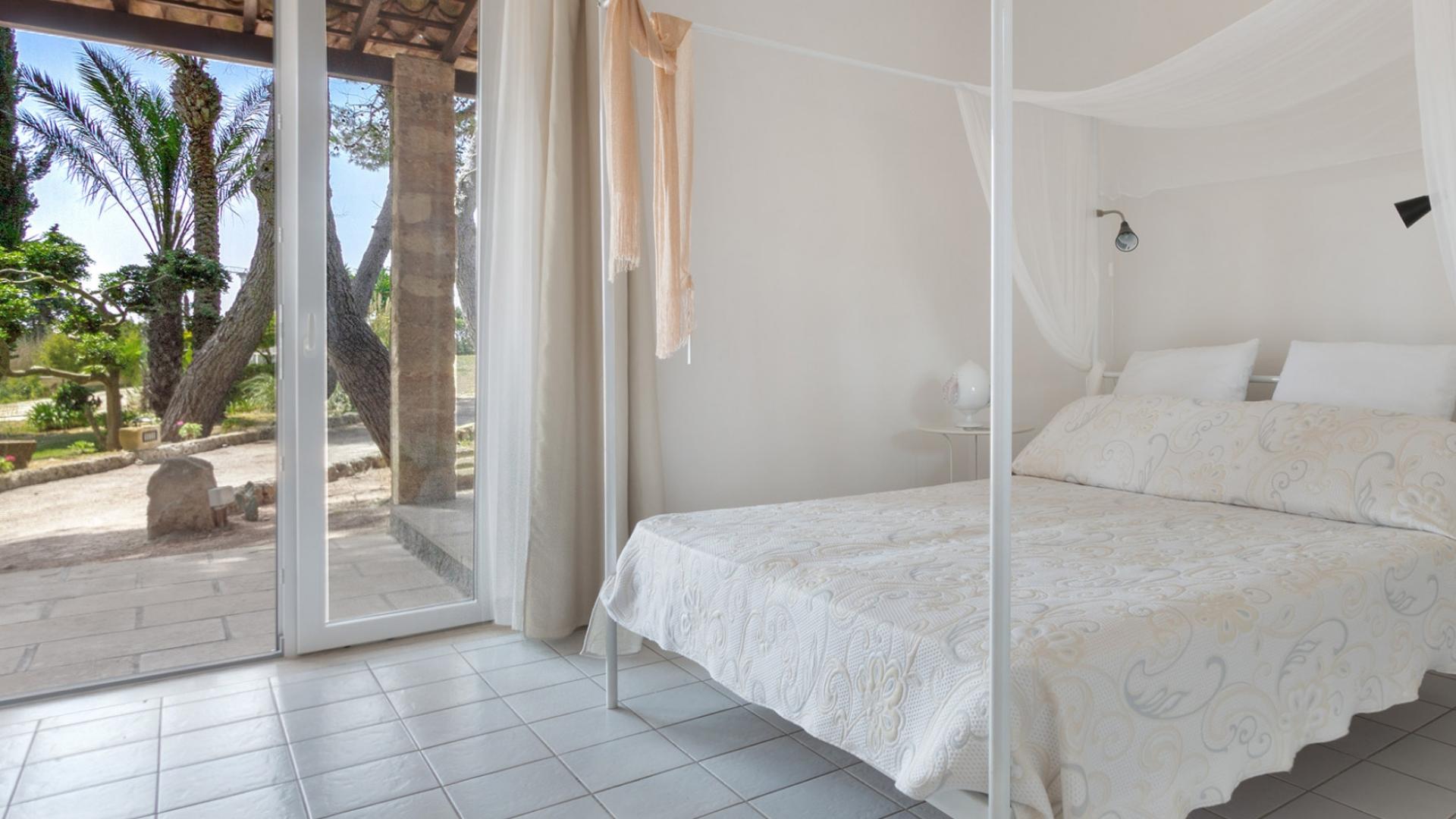 Bright room with canopy bed, garden view.