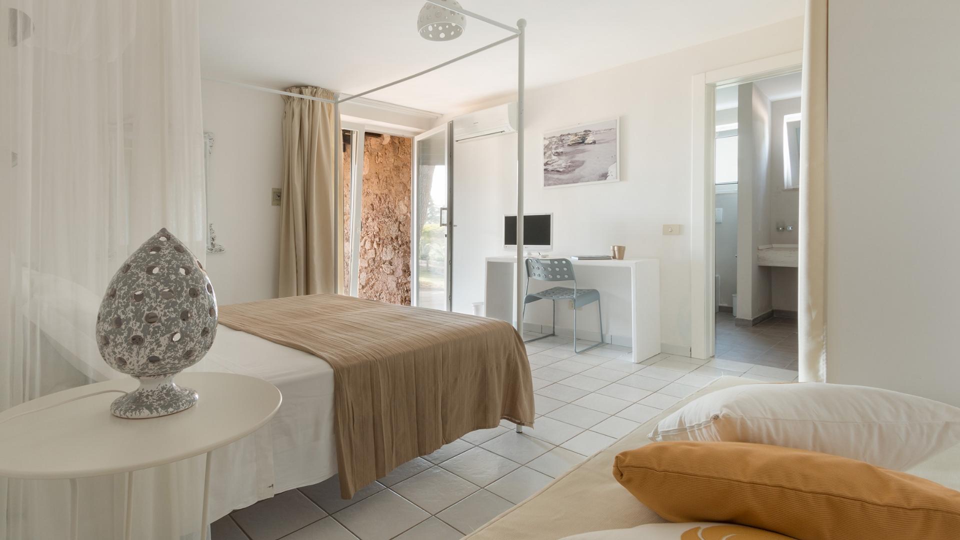 Bright room with canopy bed, desk, and private bathroom.