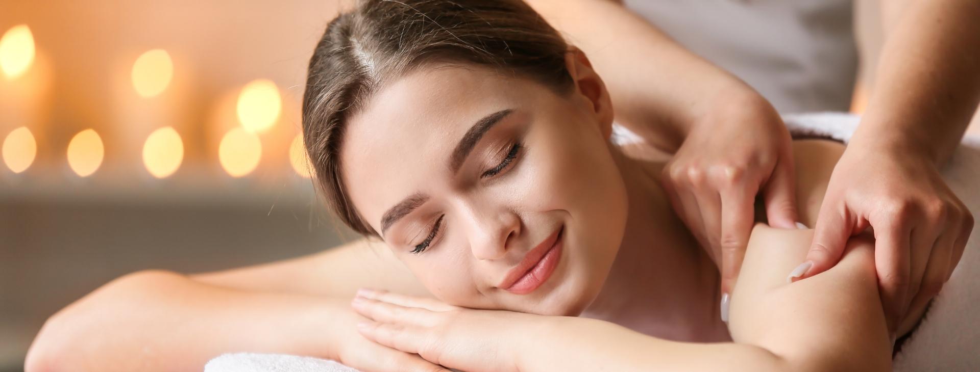 Relaxed woman receiving a massage with candles in the background.