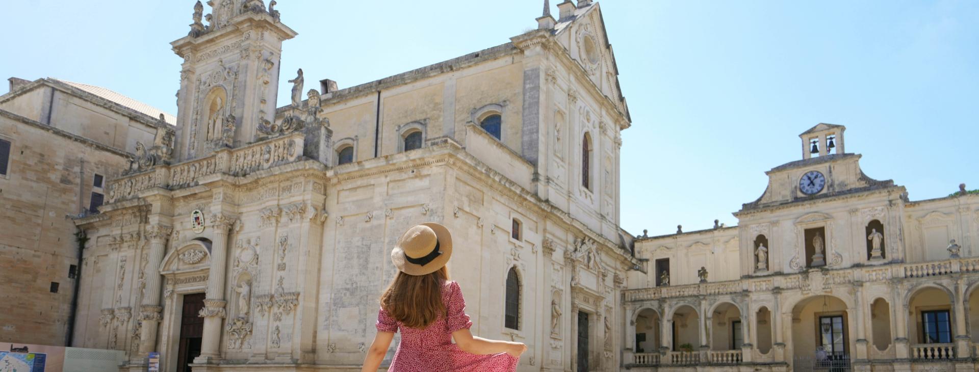 Woman with hat admiring a historic cathedral on a sunny day.