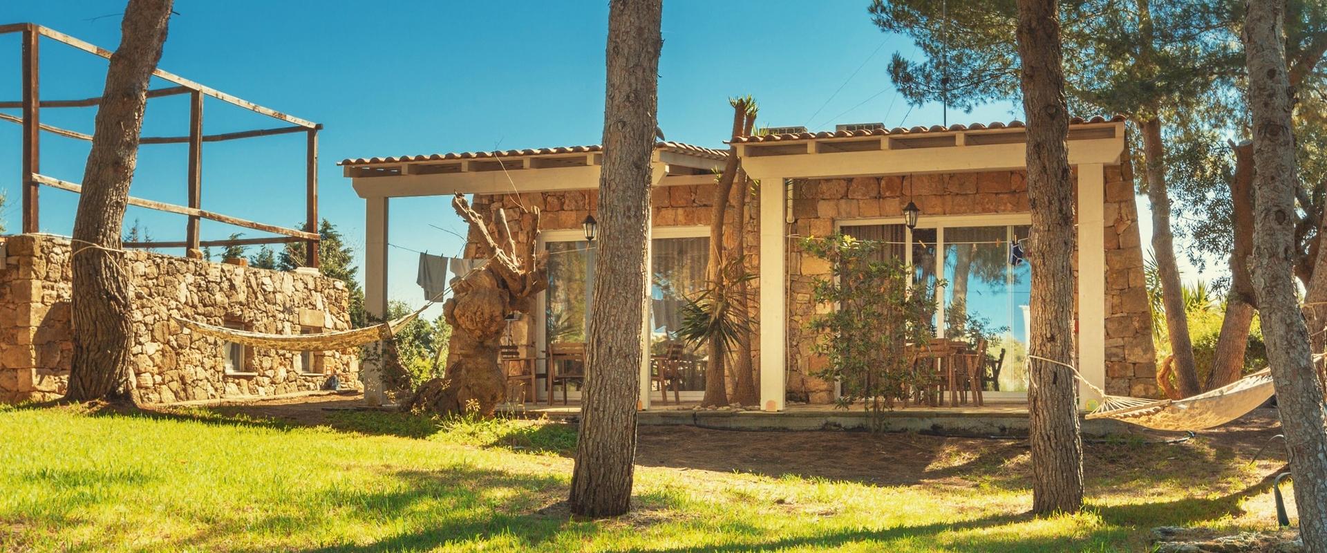 Stone house with hammocks, surrounded by nature.