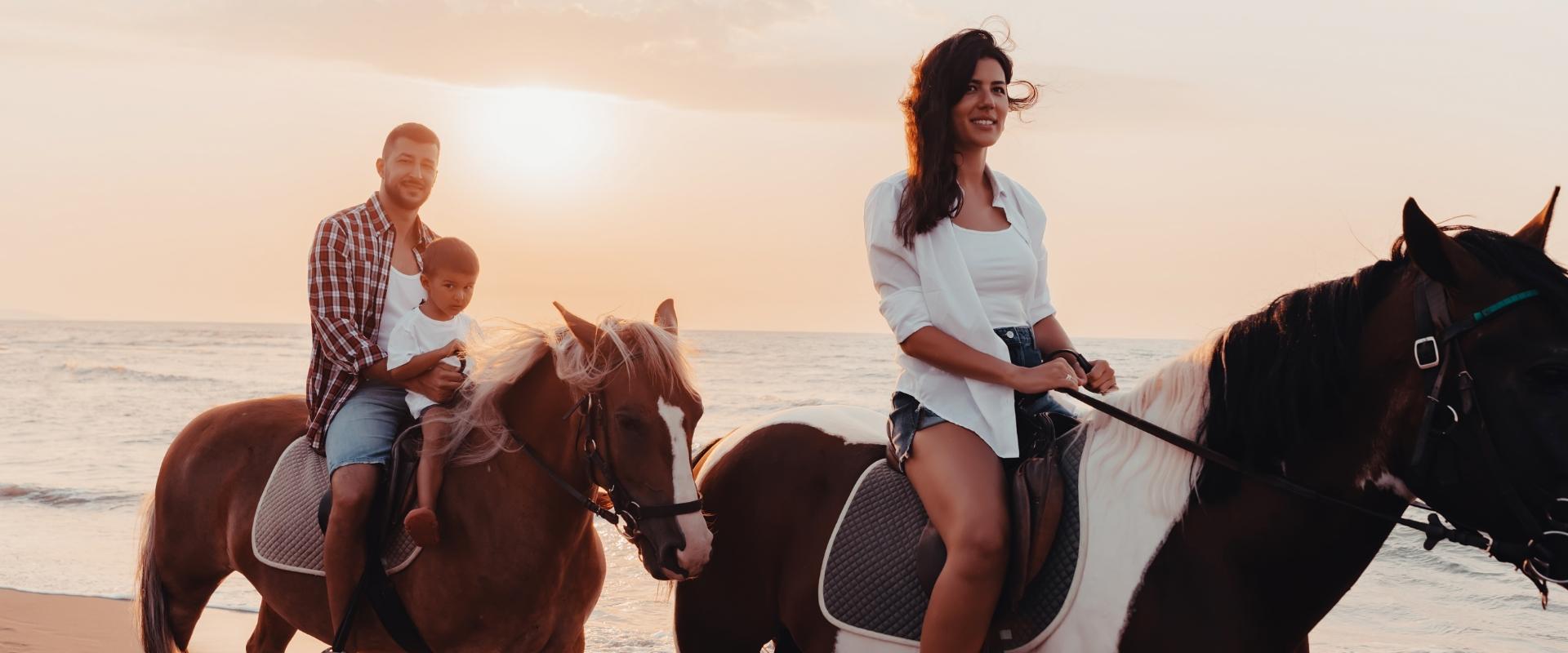 Family horseback riding on the beach at sunset, happy and relaxed.