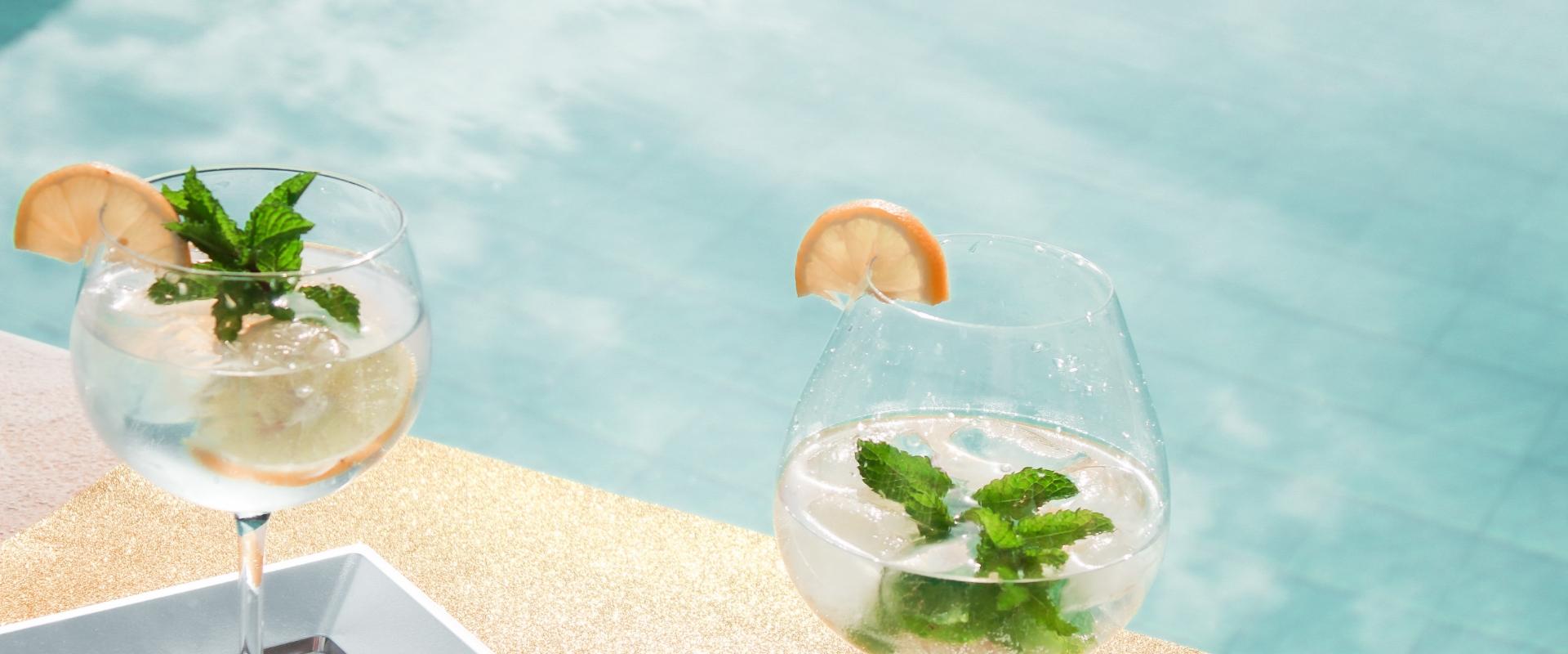 Two cocktails with lemon and mint by the pool.