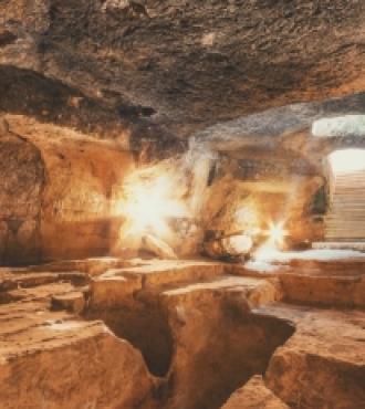 Antica grotta con illuminazione calda e scalini in pietra.