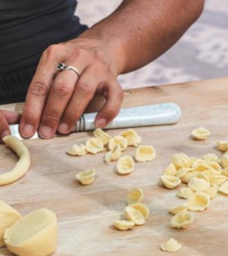 Making handmade orecchiette pasta on a wooden table.