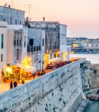 Sunset over a charming coastal town with historic buildings and warm lights.