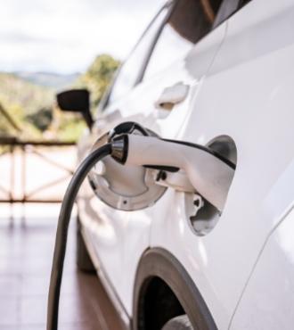 White electric car charging with cable connected to the socket.