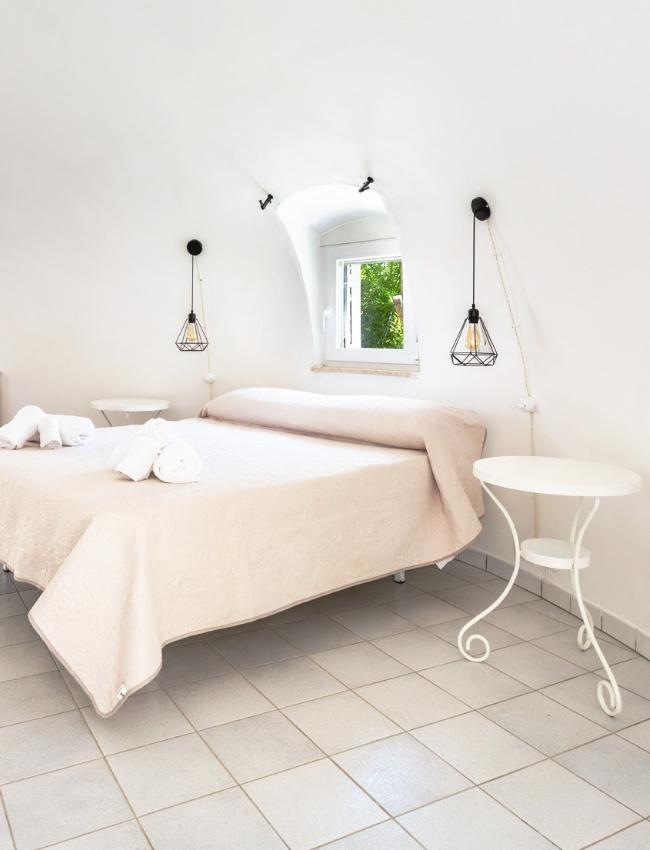 Bright bedroom with a double bed and minimalist white furnishings.