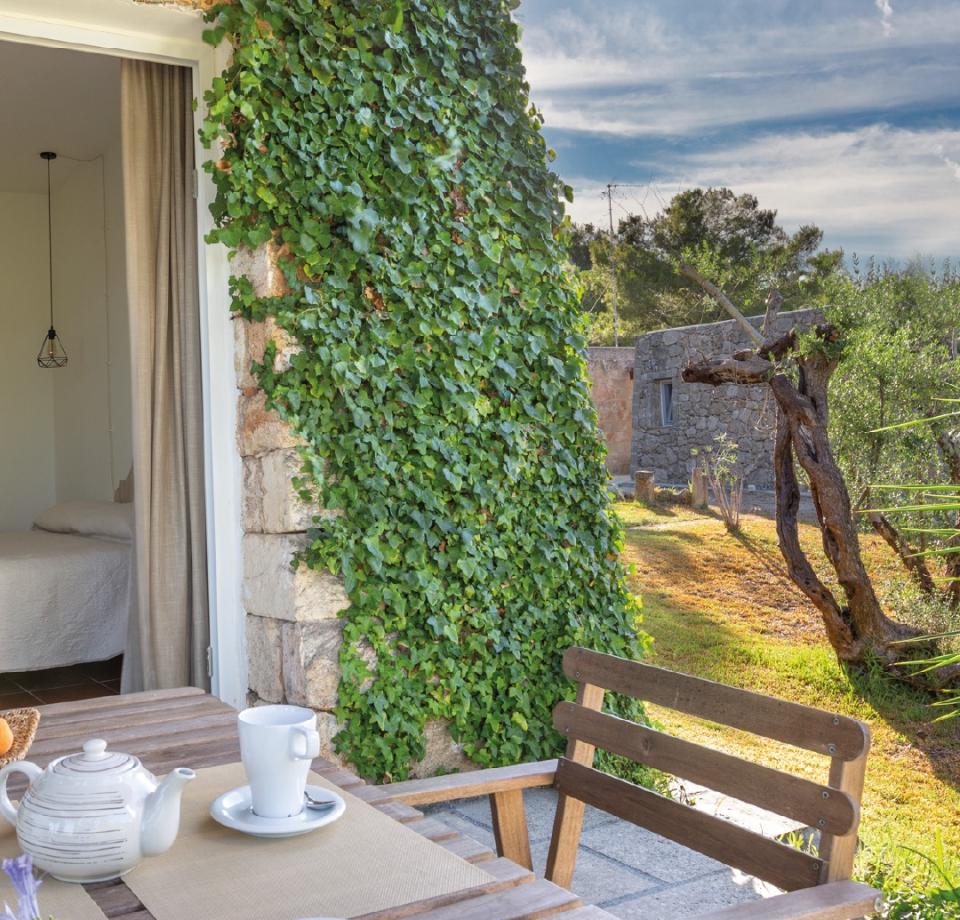 Stone house with ivy, patio for outdoor breakfast.