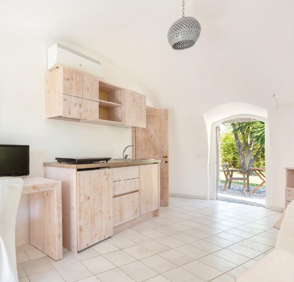 Minimalist kitchen with light wood furniture and direct access to the garden.