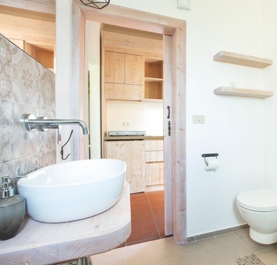 Bagno moderno con lavabo, bidet, wc e scaffali in legno.