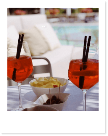 Due spritz con patatine e olive vicino alla piscina.