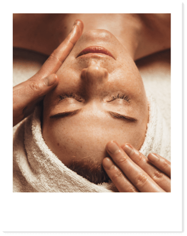 Relaxed person during a facial treatment with hands on forehead.